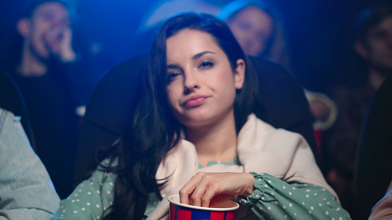 Disappointed female person visiting bad film in cinema