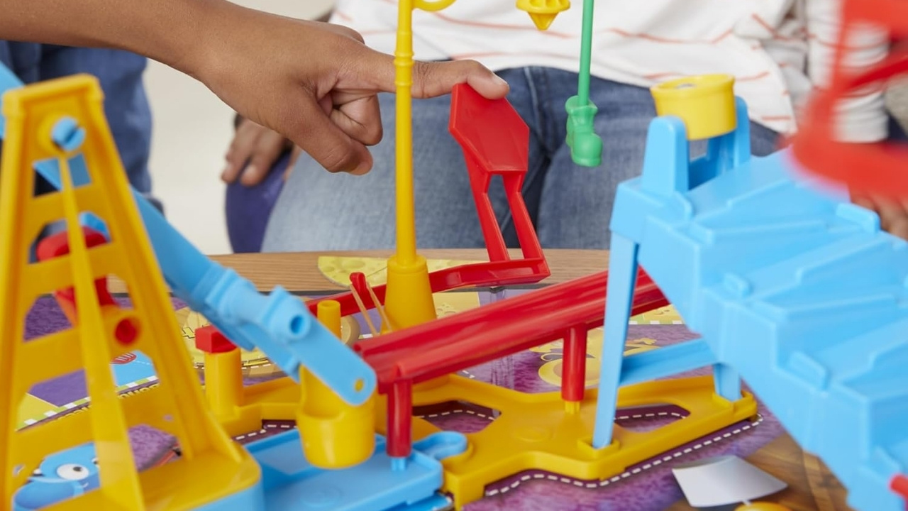 Close-up of a child's hand navigating a Mouse Trap game board and accessory pieces. 