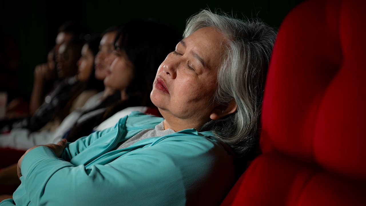 Woman asleep in theater during movie 