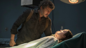 Joel Miller (Pescal) stands over Ellie Williams (Ramsey) as they lay in a hospital bed.