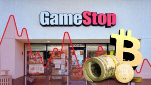 GameStop storefront in background. In foreground, tangible Bitcoin sits next to roll of standard U.S. banknotes.