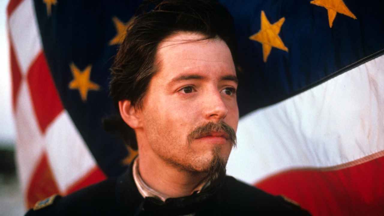 Man with dark hair and a goatee gazes to the right, in period clothing, with large flags in the background. 🎮 Outrun Gaming
