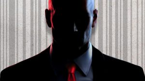 'HITMAN' protagonist Agent 47 shown obscured in foreground. Behind him, his barcode tattoo shown faded over textured background.