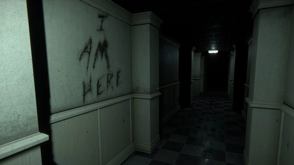 Screenshot from 'The Mortuary Assistant' shows view down long hospital corridor. A message is scrawled into the wall on the left: "I AM HERE"